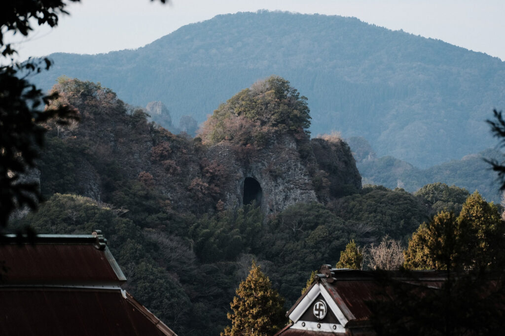 国内最大級の磨崖仏-国東半島の-熊野磨崖仏-豊後高田市-手前から建物は胎蔵寺-穴開きの山-その先の山は